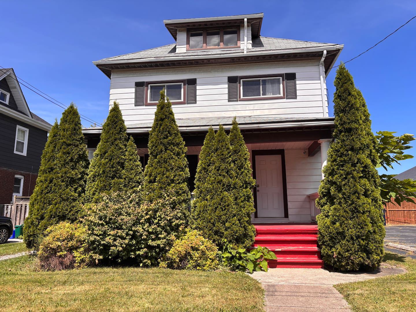 Maison Doucet from the street, with its porch and cedars